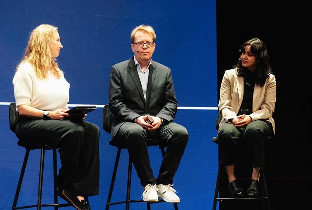 Three speakers seated on stools for an on-stage conversation